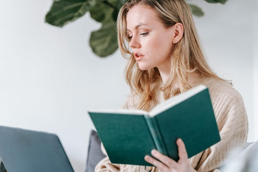 Professional woman holding a book in a modern black-and-gold office, symbolizing focus, learning, and success.