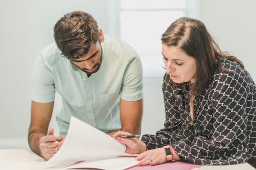 Man and woman reviewing business documents together in a modern office, symbolizing collaboration and strategic decision-making.