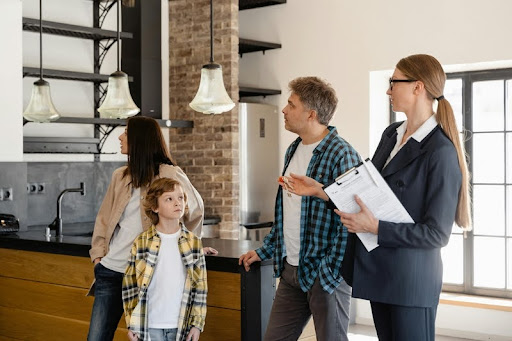 A real estate agent shows a smiling family around a modern home, discussing key features in a bright living room.