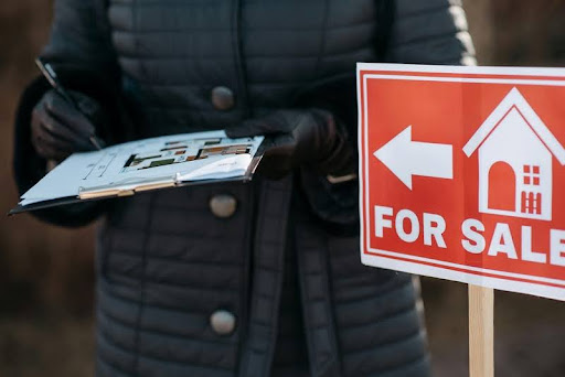 Person holding a file beside a modern “For Sale” banner, symbolizing professional real estate branding and property success.