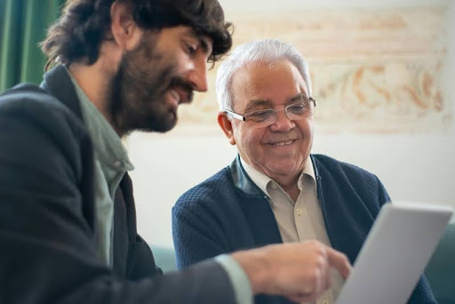 Real estate agent showing a client property details on a tablet in a modern, well-lit office setting.