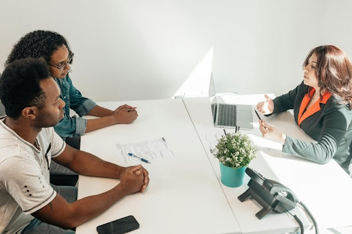 Three professionals in modern black, white, and gold setting discuss business strategies around a sleek table.