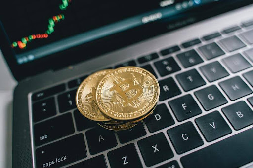Gold Bitcoin digital asset coins resting on a dark laptop keyboard, representing the shift to financial autonomy and personal wealth management.