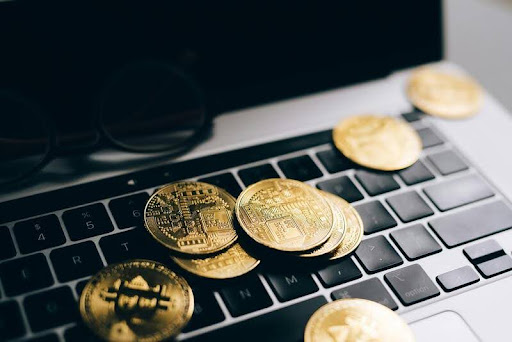 Laptop on a minimalist table with gold bitcoins, symbolizing digital finance, crypto trading, and modern wealth management.