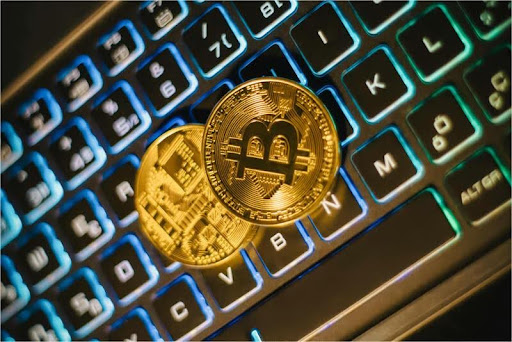 Gold Bitcoin coins resting on a sleek laptop keyboard, symbolizing digital finance, crypto trading, and blockchain technology.