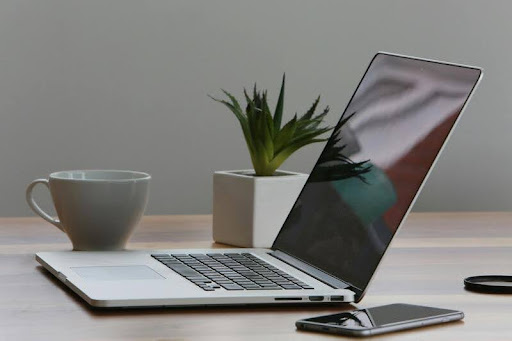 Phone and laptop on a sleek black table with gold accents, showing digital tools for work and online interaction.