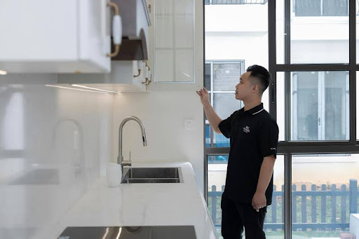 Man inspecting a sleek modern kitchen with minimalist black, white, and gold accents during a home evaluation.