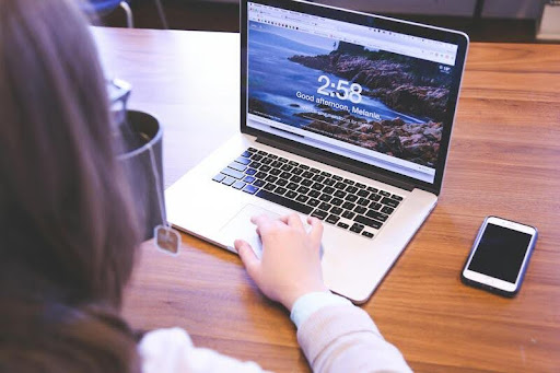 Woman working on a laptop at a minimalist desk, focused and relaxed, with soft lighting that reflects a modern, professional workspace.
