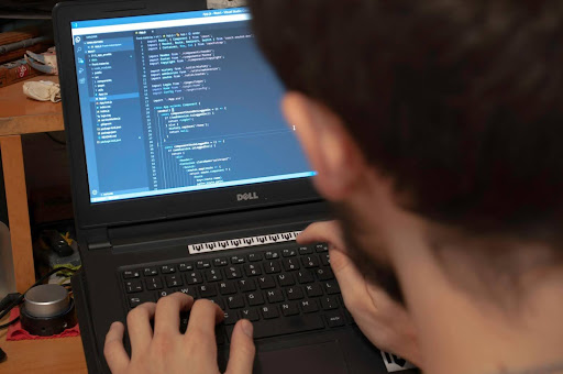 Man working on a laptop in a modern black-and-gold office, focused on digital tasks in a clean, minimalist workspace.