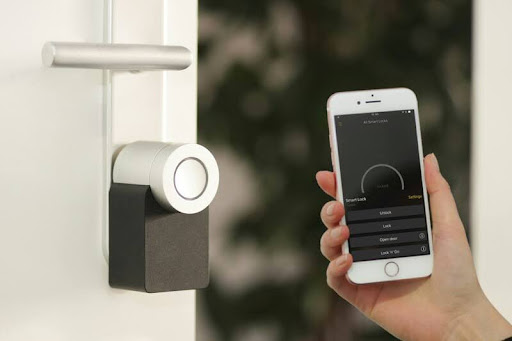 Person unlocking a modern home door using a smartphone, showcasing smart home convenience and secure technology.