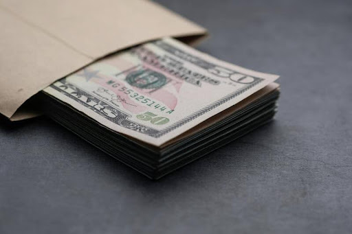 Crisp dollar bills tucked inside a minimalist white envelope, symbolizing budgeting, savings, and smart money management.