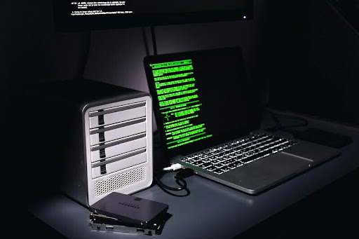 Laptop and desktop displaying code on a modern black-and-white workspace, reflecting software development and digital innovation.