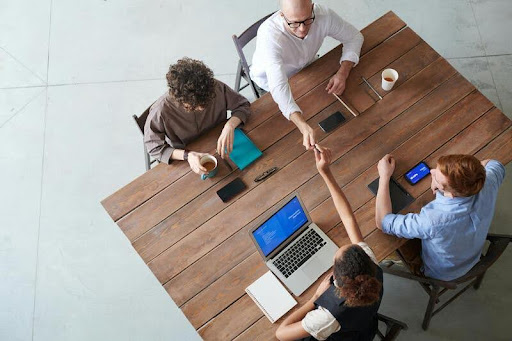 Entrepreneurs collaborating around a table, discussing strategies in a modern, minimalist workspace with black, white, and gold accents.