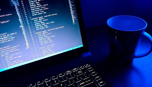 Computer displaying lines of code on a sleek desk with modern black-and-gold accents, highlighting a clean, minimalist workspace.