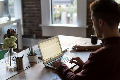 Man focused on a laptop at a sleek desk, working in a modern, minimalist workspace with gold, black, and white accents.
